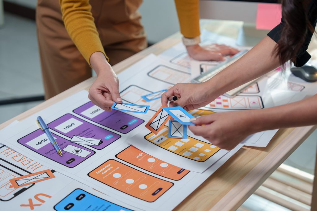 Web designers collaborating on developing a mobile application, arranging various options for the us